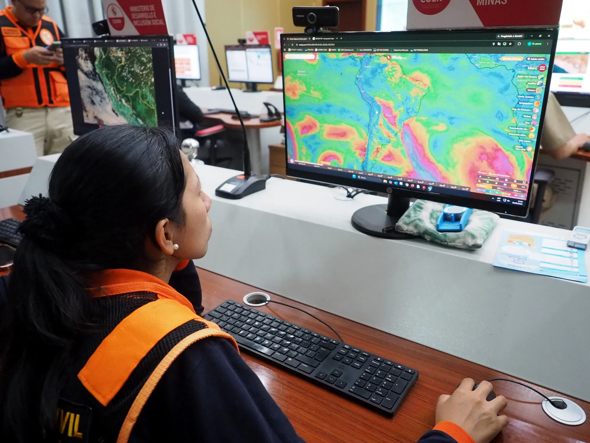 A woman examines a computer screen with a weather pattern on it