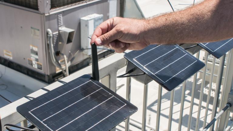 A man holds an antenna on a tiny solar panel
