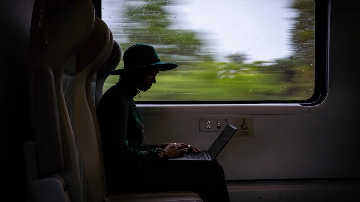 A passenger on a Brightline train is seen in silhouette as scenery flashed by outside the window next to her.