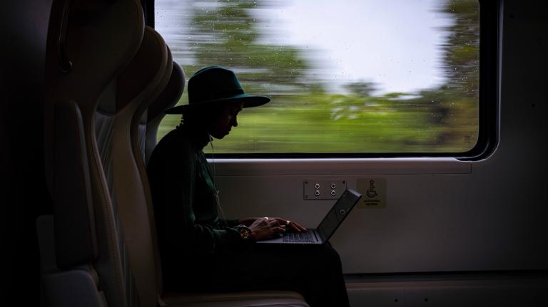 A passenger on a Brightline train is seen in silhouette as scenery flashed by outside the window next to her.