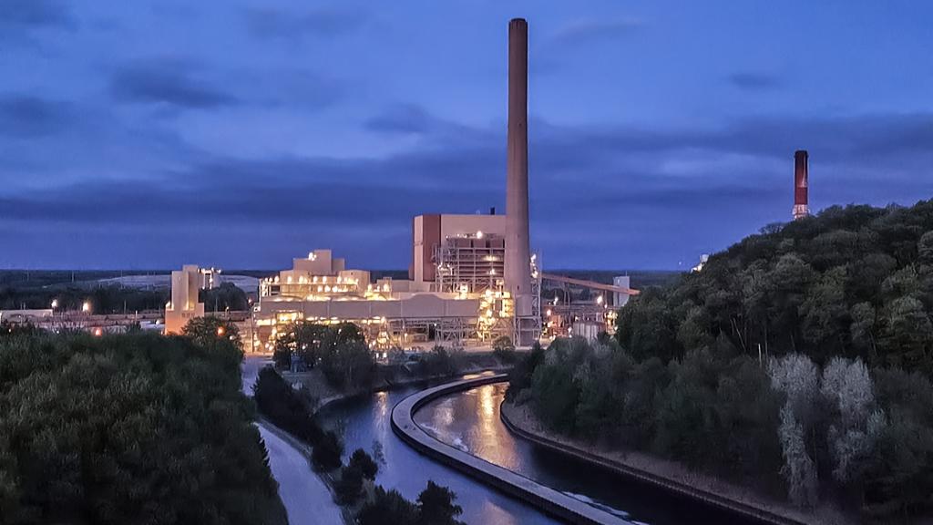 photo of coal plant and smokestacks at night with trees and a river