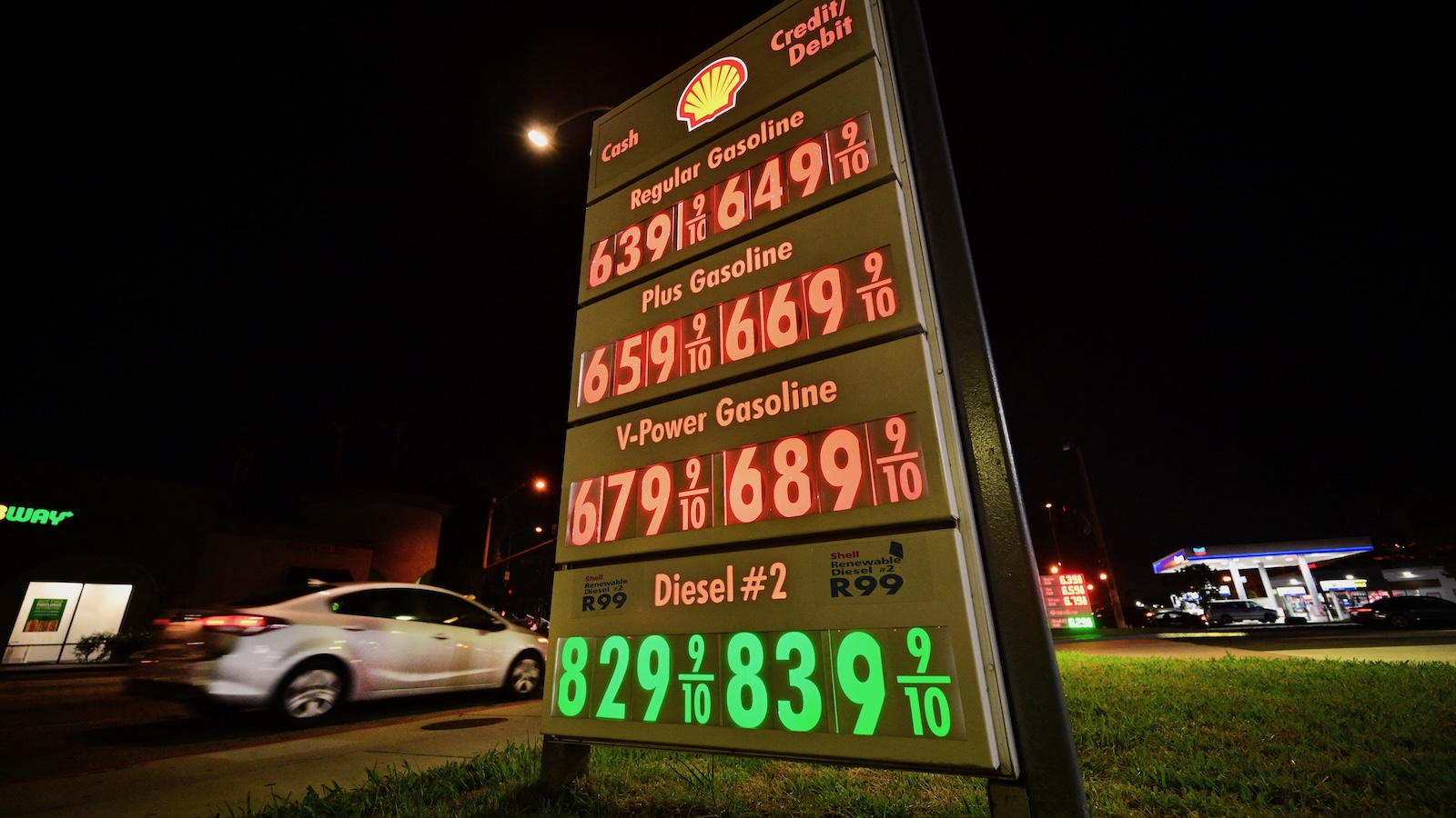 A motorist pulls into a gas station where the marque lists gas prices that include diesel fuel for eight dollars and twenty-nine cents a gallon.