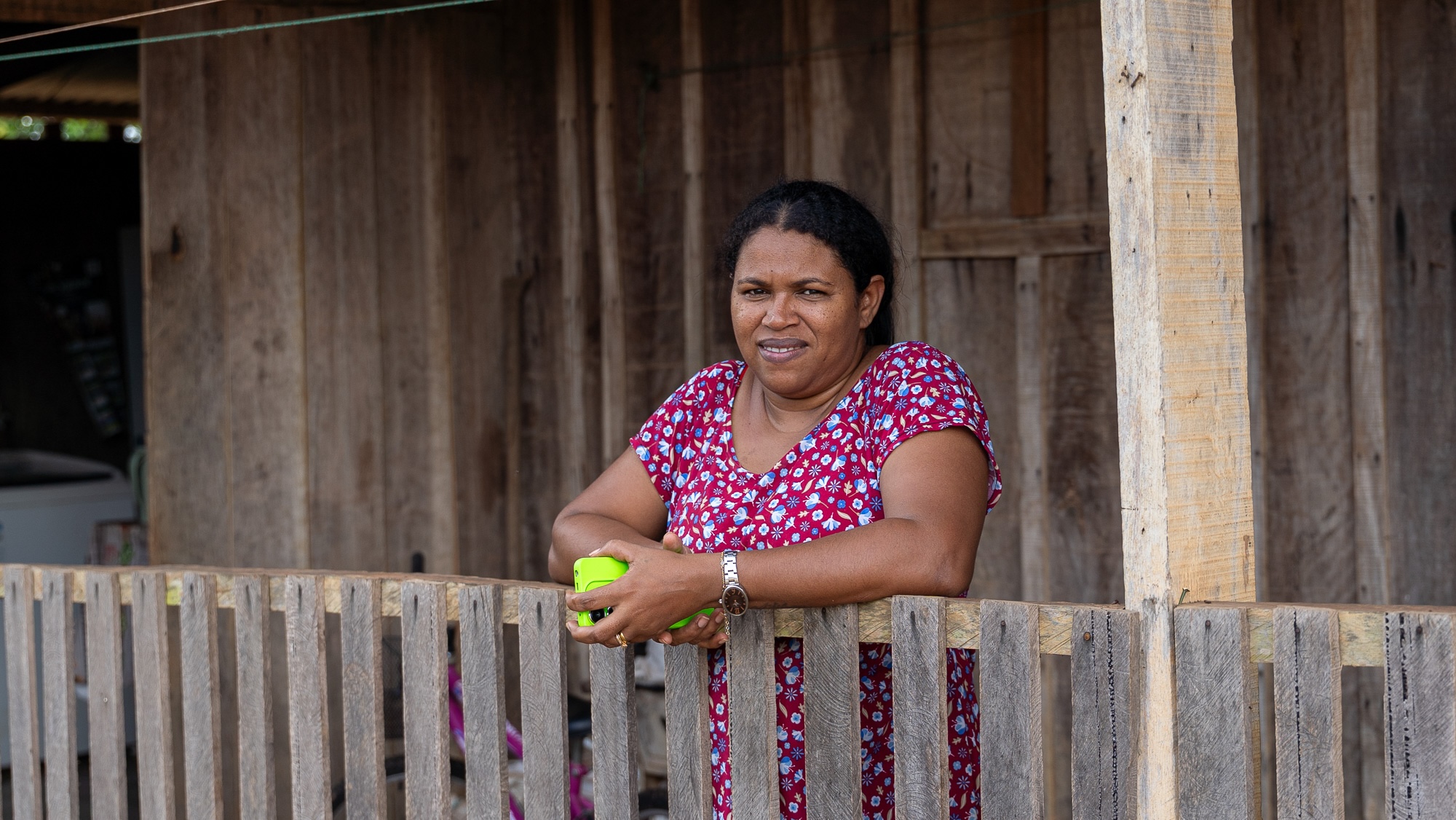 A woman poses for a photo on the porch of a wooden house