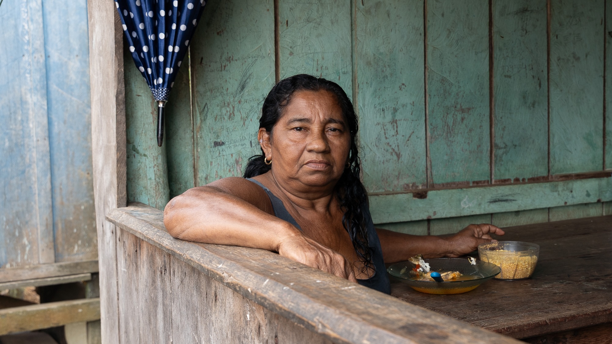 a woman eats a meal under the awning of a wooden house