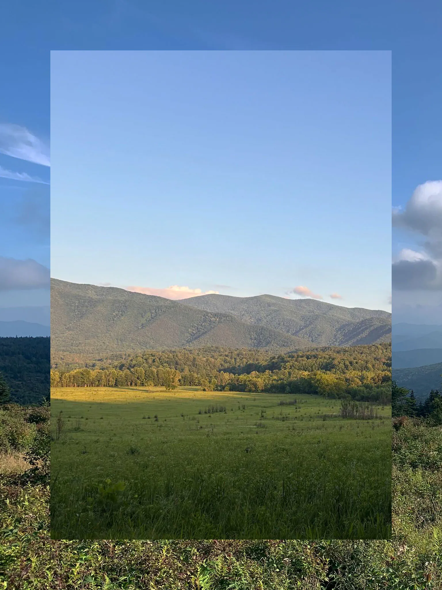 A collage consisting of two vertical photos, the outside functioning a border and the inside fully visible. The outside photo is a field with rolling slopes and a blue sky with mountains. The inner photo is a field with faraway trees and sloping hills.
