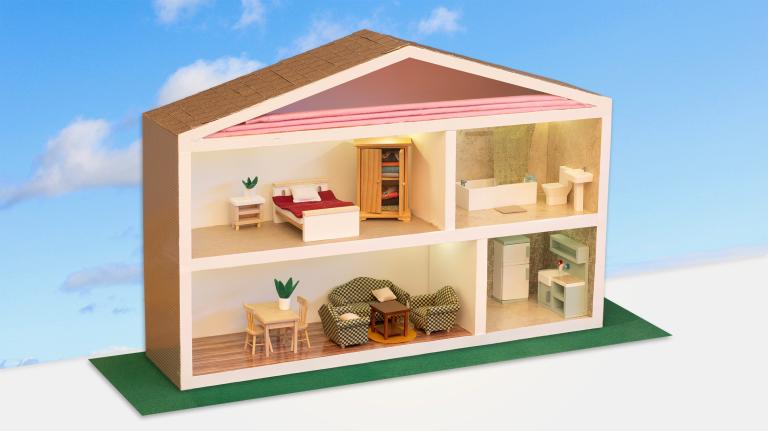 A miniature house made of wood with a cutaway to rooms like a dollhouse. The cutaway shows an attitc with insulation, a bedroom, a kitchen, a living room, and a bathroom. The house sits on a green screen replaced background with blue skies and clouds.