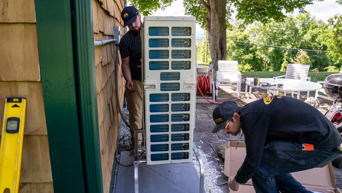 Two men moving a heat pump