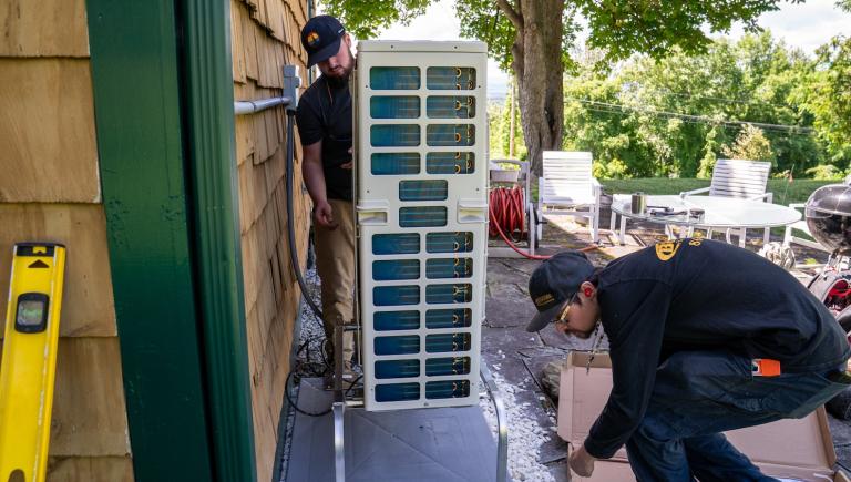 Two men moving a heat pump