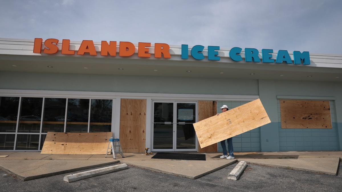 Workers board up the windows of restaurant in Gulf Breeze, Florida, to prepare for Hurricane Isaias.