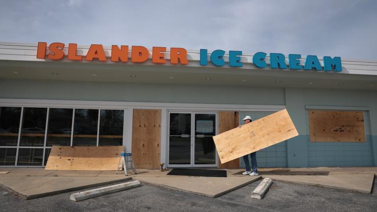 Workers board up the windows of restaurant in Gulf Breeze, Florida, to prepare for Hurricane Isaias.
