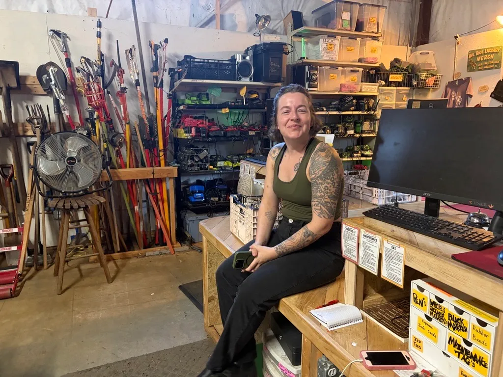 A woman sits in a workshop surrounded by tools
