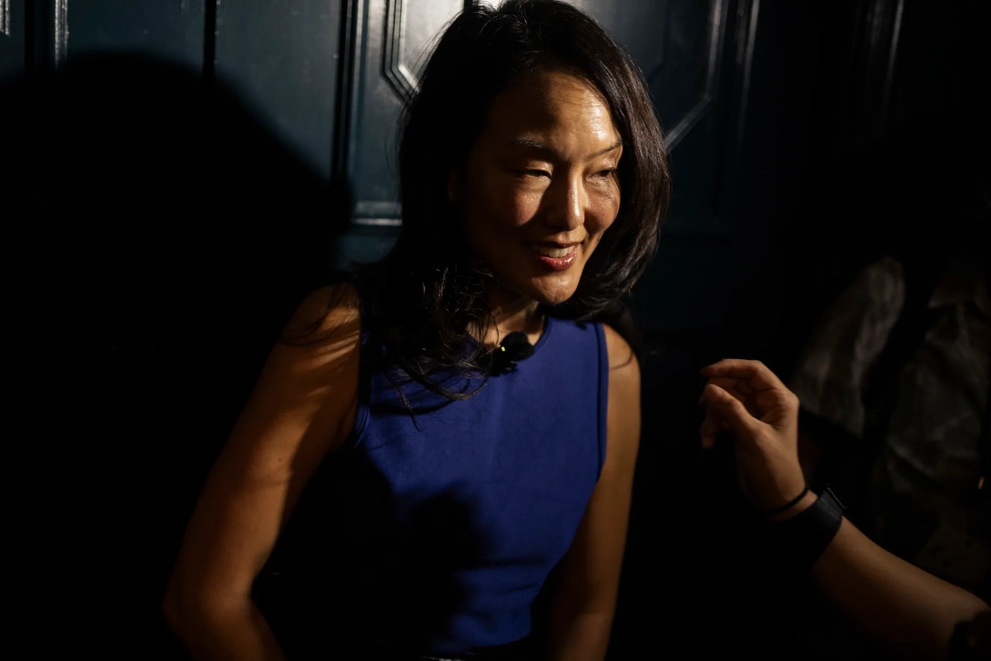 A woman smiles standing near a door