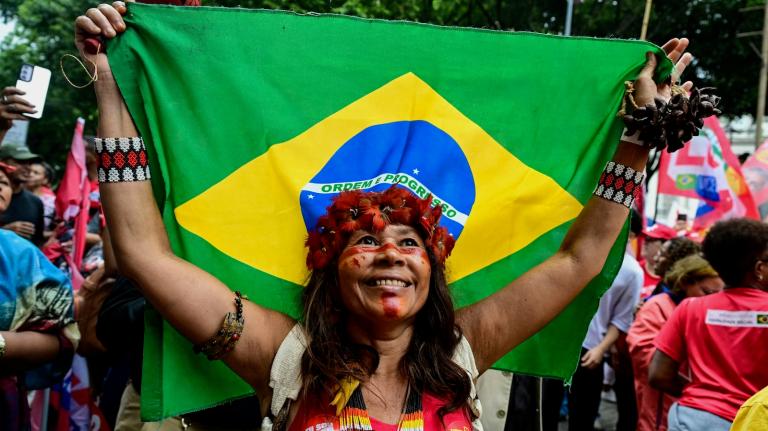 An Indigenous woman who supports Brazilian president Luiz Inácio Lula da Silva carries a national flag during a campaign event.