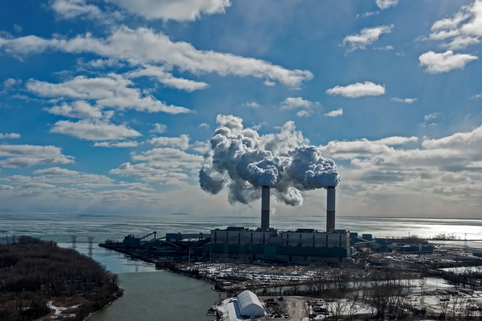A power plant at the mouth of a river emits white clouds