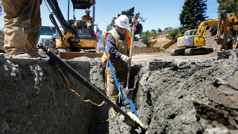 A man in a hard hat digs into the street