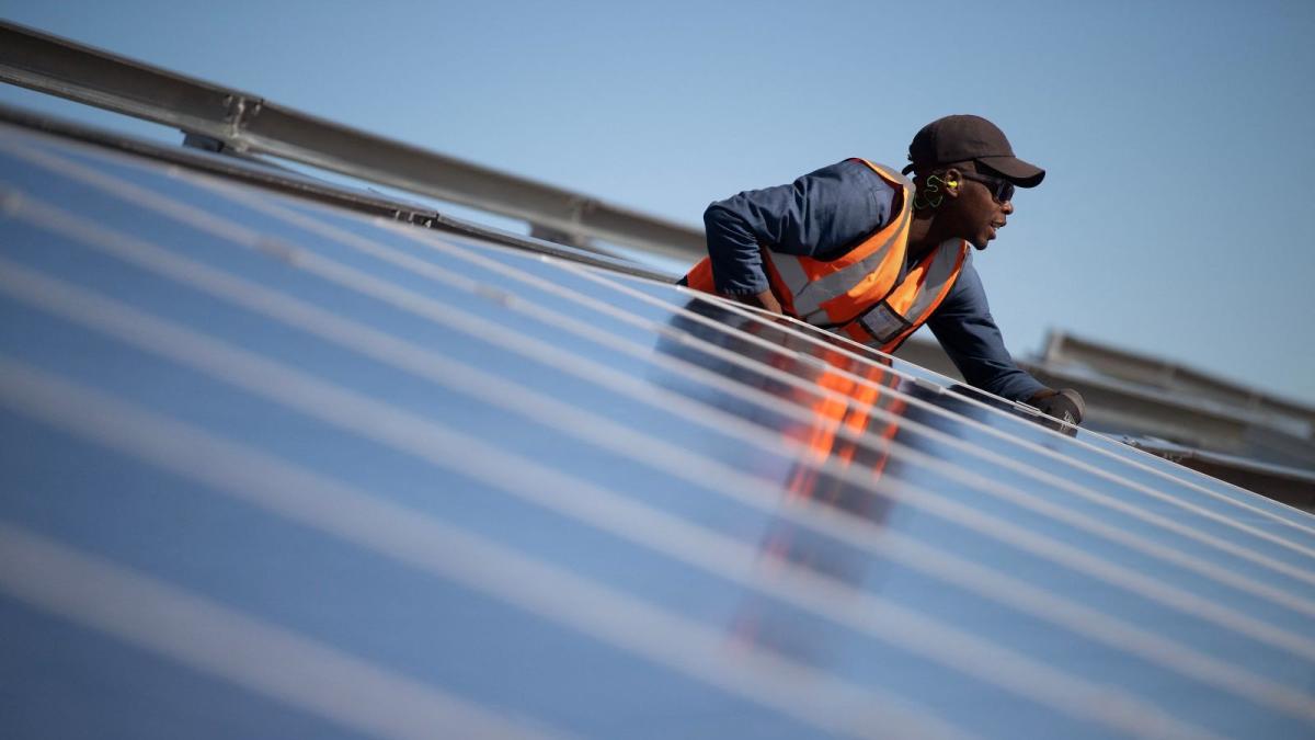 A technician installs solar panels in South Africa