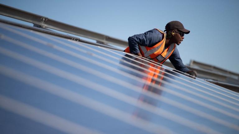 A technician installs solar panels in South Africa