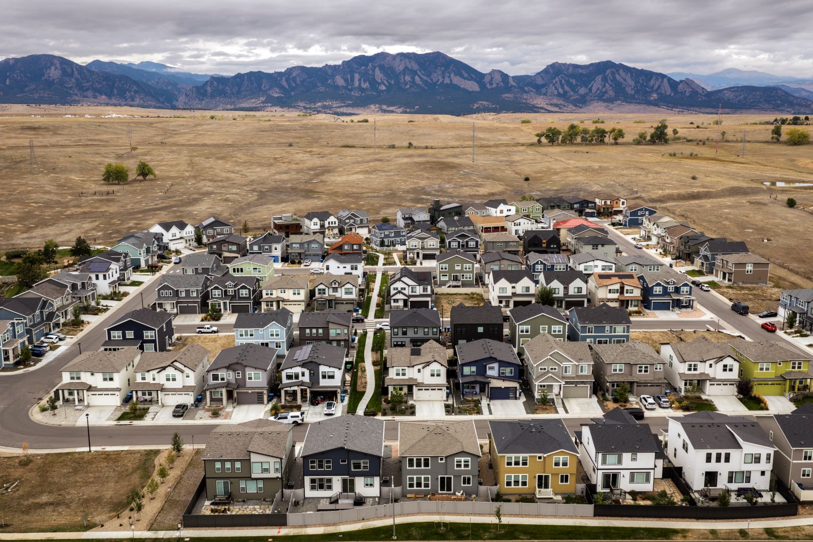 A housing development stands before the Rocky mountains