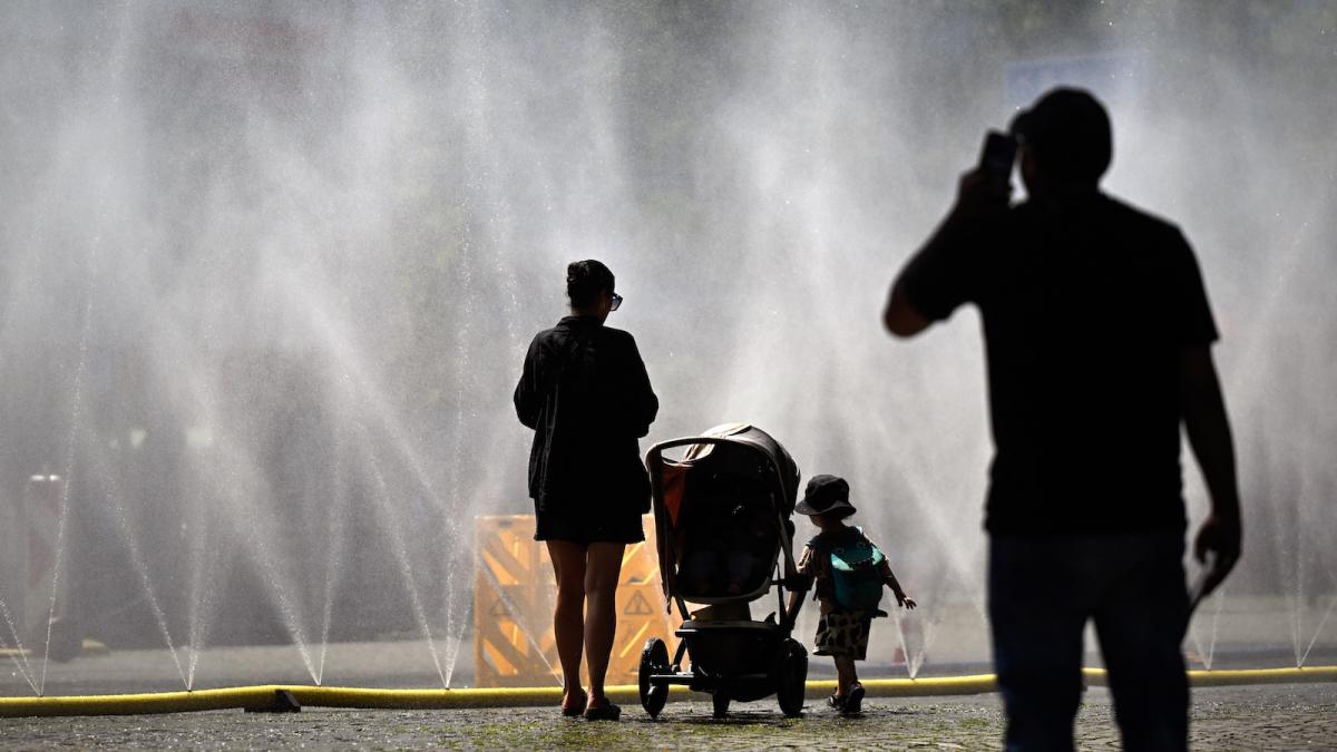A woman and a toddler cool off in a mist of water during a heatwave in Germany.