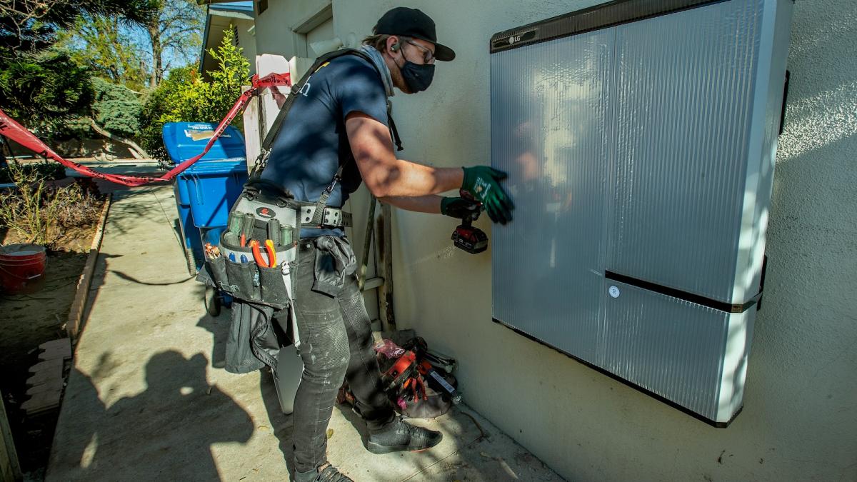 A technician installs a 215-pound lithium ion battery in a home in California.