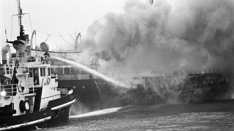 A black and white photo of a ship on fire